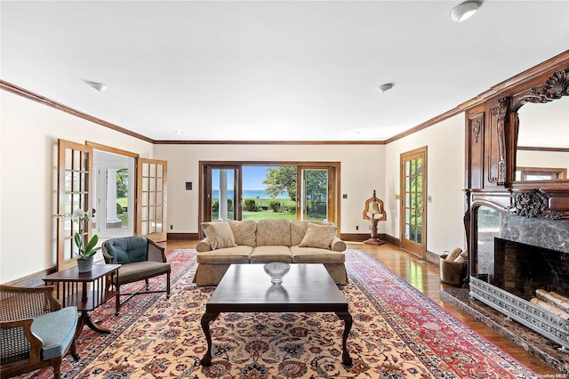 living room featuring a fireplace, crown molding, french doors, and hardwood / wood-style flooring