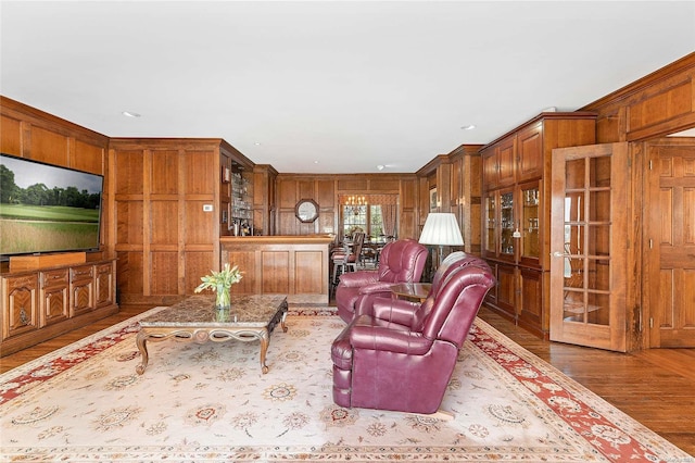 living room featuring wood walls, wood-type flooring, crown molding, and french doors