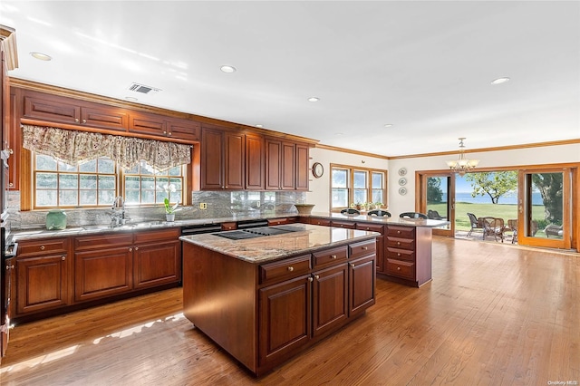 kitchen featuring light hardwood / wood-style flooring, a kitchen island, a healthy amount of sunlight, and an inviting chandelier