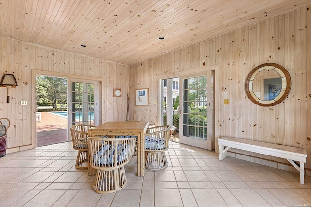 tiled dining room featuring wood ceiling and wooden walls