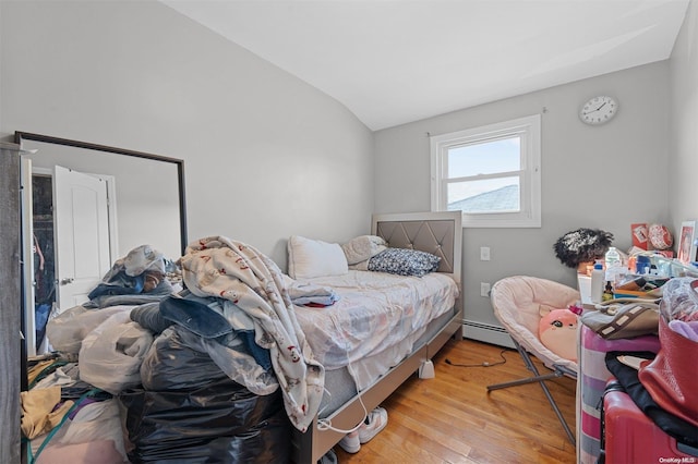 bedroom with light hardwood / wood-style flooring, lofted ceiling, and a baseboard heating unit