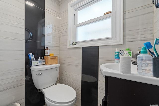 bathroom featuring vanity, toilet, and tile walls