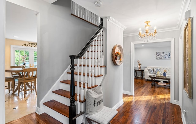 staircase with a chandelier, wood-type flooring, and crown molding