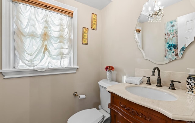 bathroom featuring vanity, a chandelier, and toilet