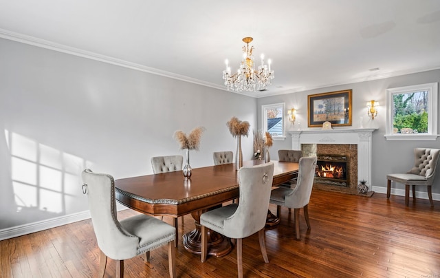 dining room featuring hardwood / wood-style flooring, crown molding, a fireplace, and an inviting chandelier