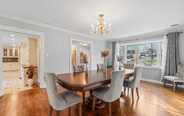 dining room featuring a chandelier, crown molding, and light hardwood / wood-style floors