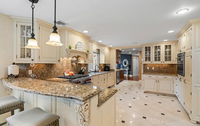 kitchen featuring kitchen peninsula, a kitchen bar, light stone countertops, stainless steel appliances, and decorative light fixtures