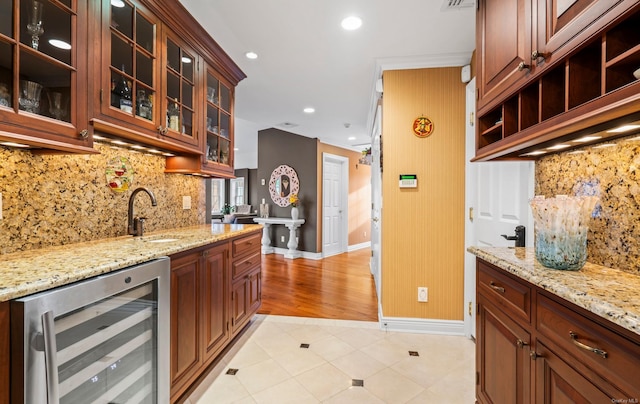 kitchen with light stone countertops, backsplash, crown molding, sink, and wine cooler