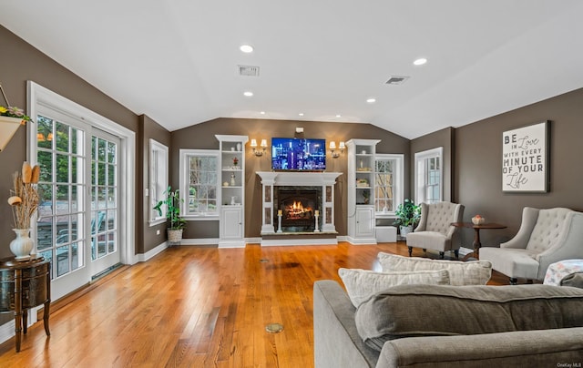 living room with a fireplace, light hardwood / wood-style floors, and lofted ceiling