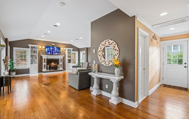 foyer featuring hardwood / wood-style floors, lofted ceiling, ornamental molding, and a healthy amount of sunlight