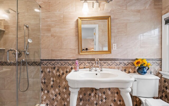 bathroom featuring a tile shower, toilet, and tile walls