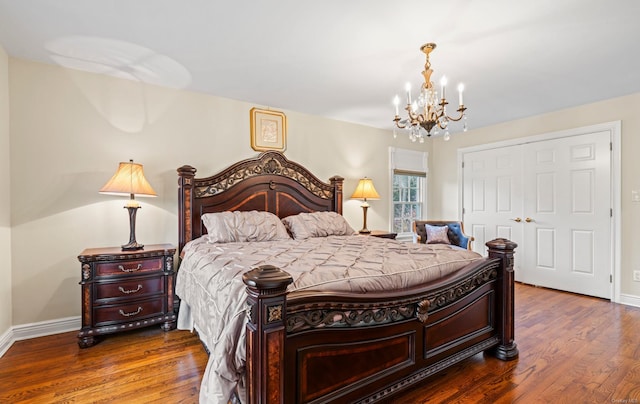 bedroom with an inviting chandelier, dark wood-type flooring, and a closet