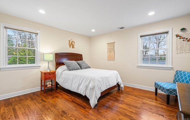 bedroom with multiple windows and dark hardwood / wood-style floors