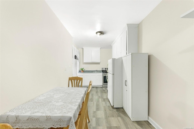 kitchen with light wood-type flooring, stainless steel range, sink, white cabinets, and white fridge