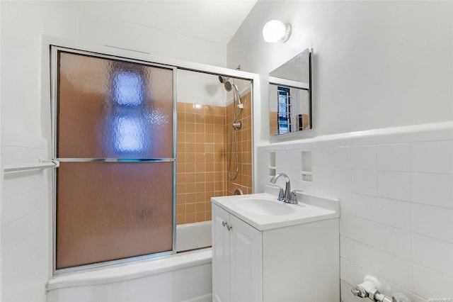 bathroom with vanity, enclosed tub / shower combo, and tile walls