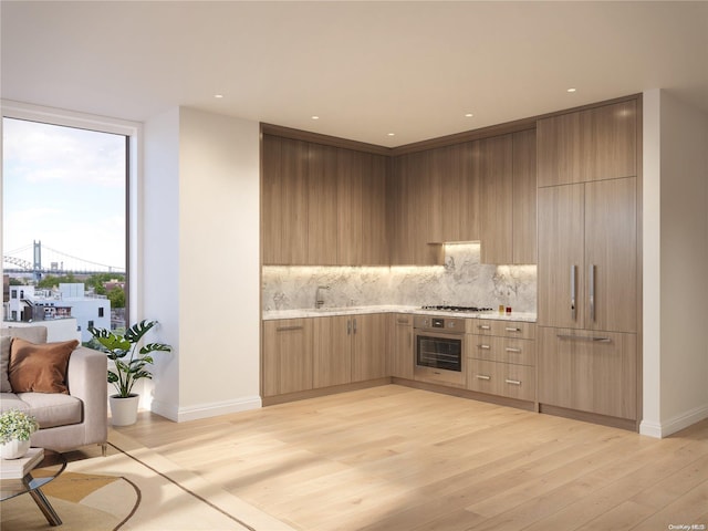 kitchen with decorative backsplash, stainless steel appliances, light hardwood / wood-style flooring, and sink