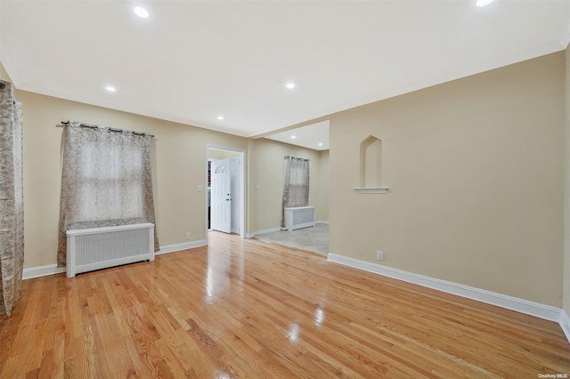 unfurnished living room featuring light hardwood / wood-style floors, radiator heating unit, and crown molding