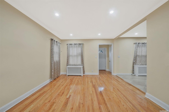 empty room featuring radiator heating unit and light hardwood / wood-style flooring