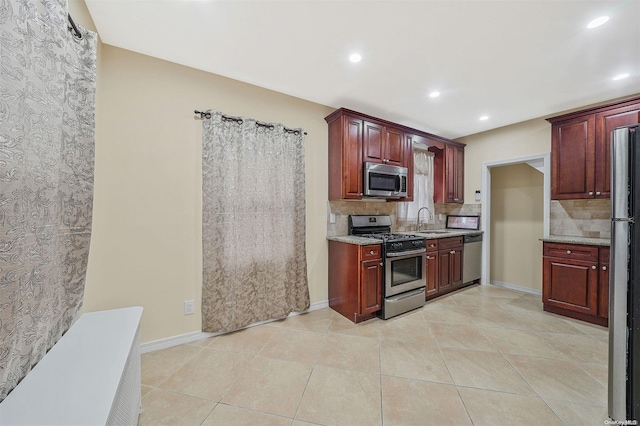 kitchen featuring appliances with stainless steel finishes, tasteful backsplash, light tile patterned floors, and sink