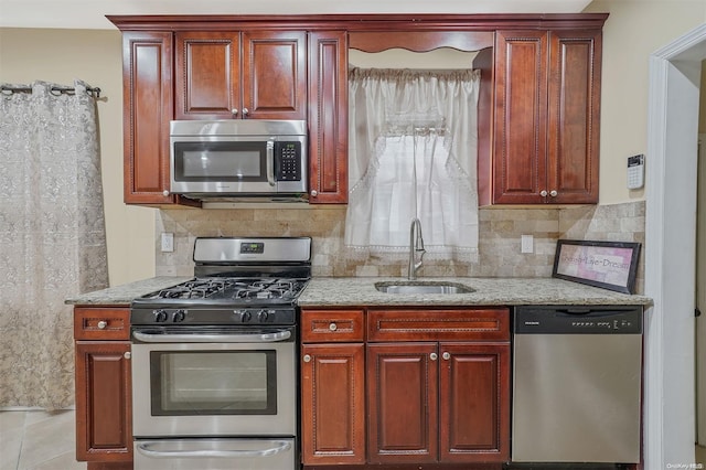 kitchen with light stone countertops, sink, decorative backsplash, light tile patterned flooring, and appliances with stainless steel finishes