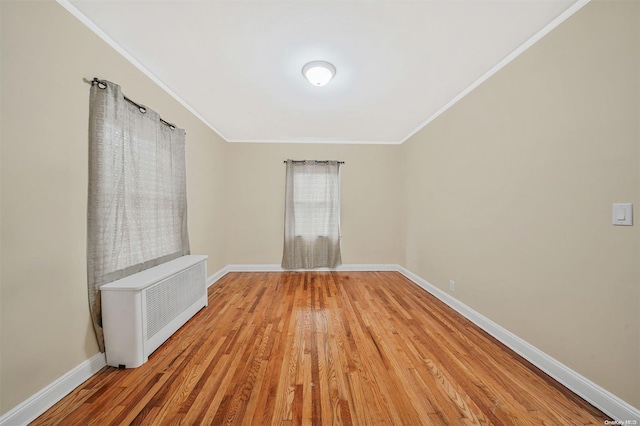 unfurnished room featuring radiator heating unit, light hardwood / wood-style flooring, and ornamental molding