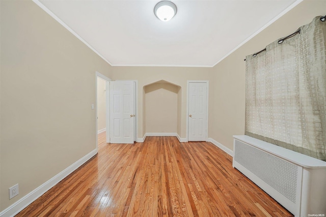 unfurnished room with ornamental molding, radiator, and light hardwood / wood-style flooring