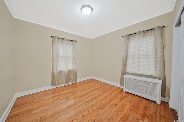 empty room featuring crown molding, radiator heating unit, and hardwood / wood-style floors