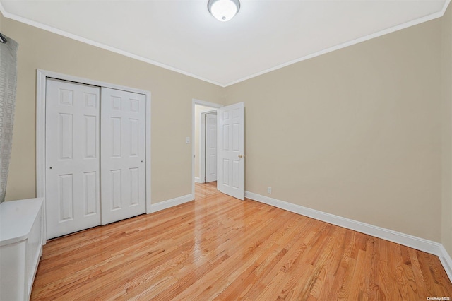 unfurnished bedroom featuring light wood-type flooring, a closet, and crown molding