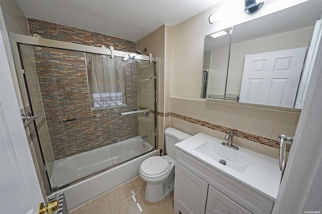 full bathroom with backsplash, toilet, shower / bath combination with glass door, vanity, and tile walls