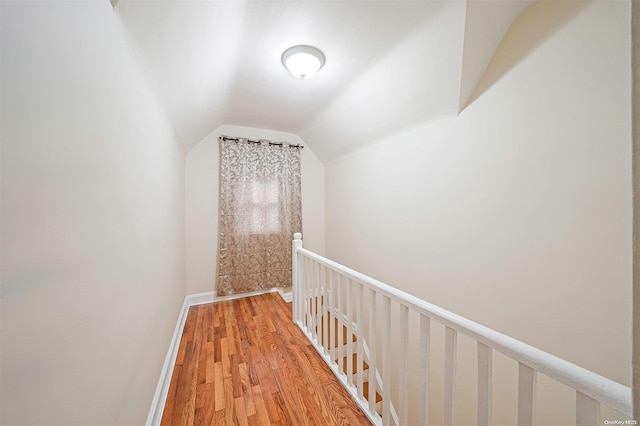 corridor with wood-type flooring and lofted ceiling