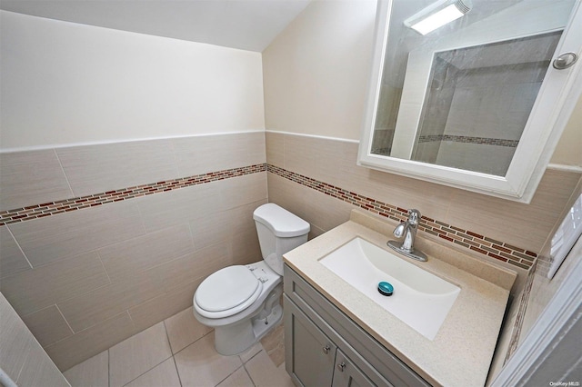 bathroom featuring tile patterned floors, vanity, toilet, and tile walls