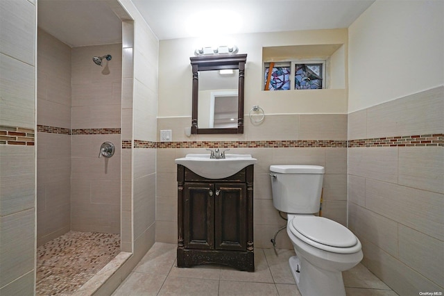 bathroom featuring vanity, tiled shower, tile walls, tile patterned flooring, and toilet