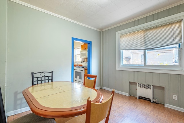 dining room featuring a wealth of natural light, radiator heating unit, light parquet flooring, and ornamental molding