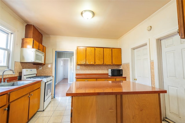 kitchen featuring white appliances, crown molding, sink, light tile patterned floors, and a kitchen island