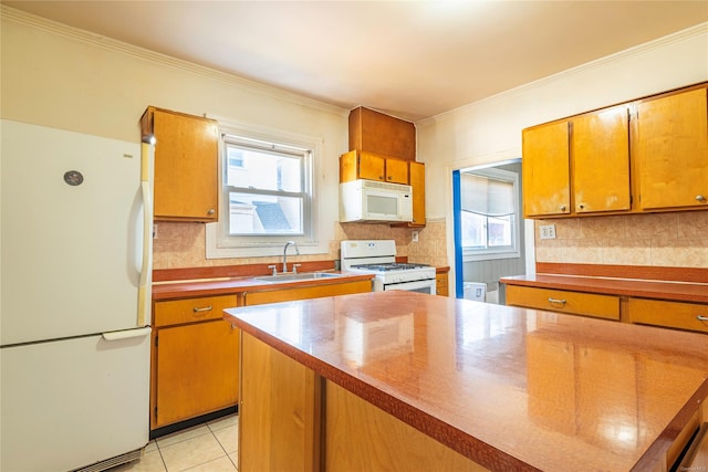 kitchen with a healthy amount of sunlight, white appliances, sink, and light tile patterned floors