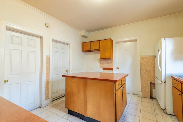 kitchen featuring white fridge, a kitchen island, ornamental molding, and light tile patterned floors