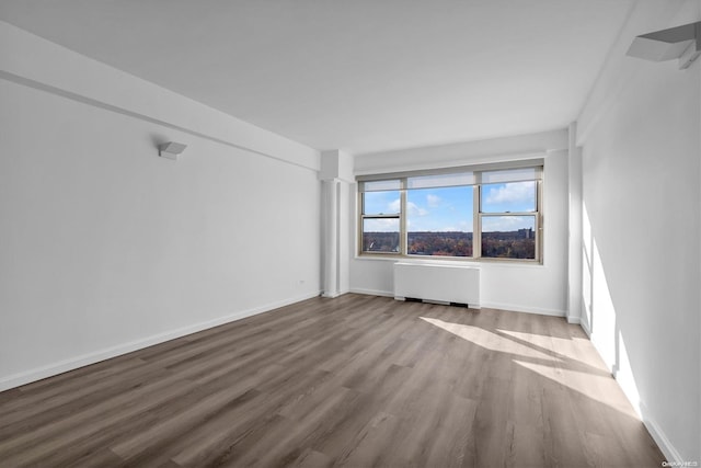 unfurnished room with radiator heating unit and hardwood / wood-style floors