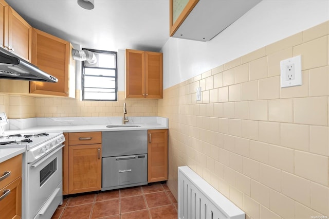 kitchen with stove, exhaust hood, sink, dark tile patterned flooring, and tile walls