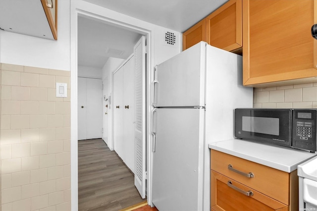 kitchen featuring decorative backsplash, white fridge, and dark wood-type flooring