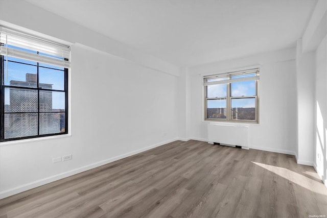 empty room with light hardwood / wood-style floors and radiator