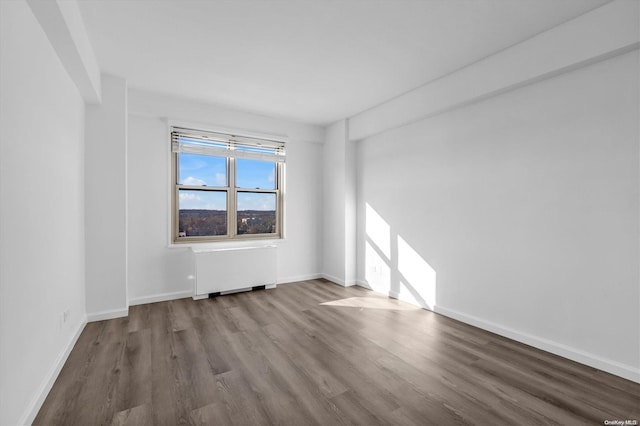 empty room with wood-type flooring and radiator