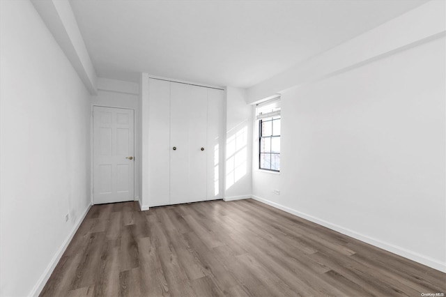 unfurnished bedroom featuring wood-type flooring and a closet