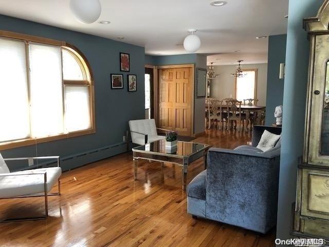 living room with wood-type flooring, baseboard heating, and a wealth of natural light