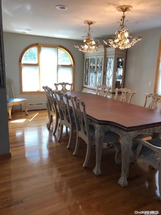 dining space with light wood-type flooring, a baseboard radiator, and a notable chandelier