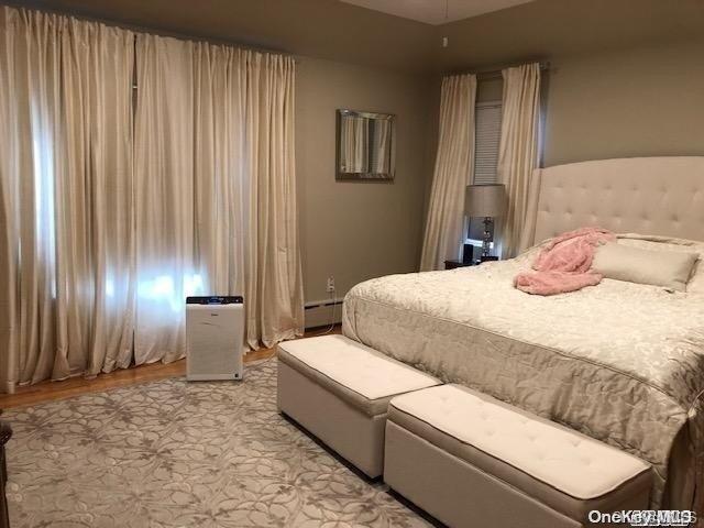 bedroom with baseboard heating and light hardwood / wood-style floors