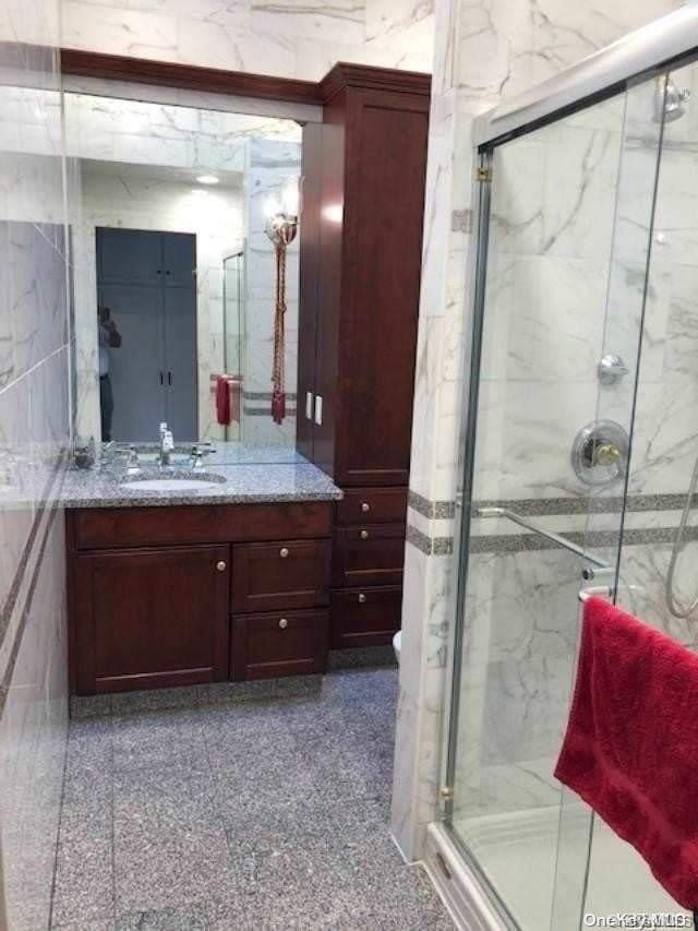 bathroom featuring an enclosed shower, vanity, and tile walls