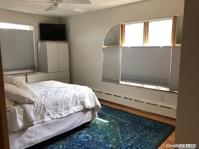 bedroom featuring ceiling fan, wood-type flooring, and baseboard heating