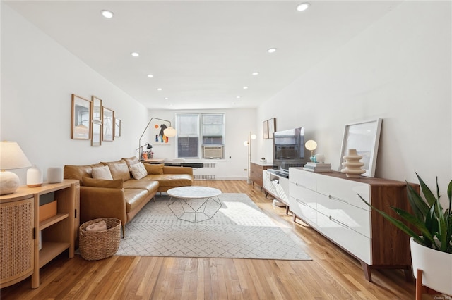 living room featuring light hardwood / wood-style flooring, cooling unit, and radiator heating unit