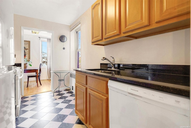 kitchen with radiator, dark stone counters, white dishwasher, sink, and dark hardwood / wood-style flooring