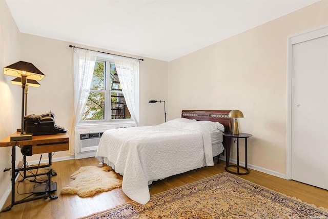 bedroom featuring hardwood / wood-style flooring and a wall unit AC